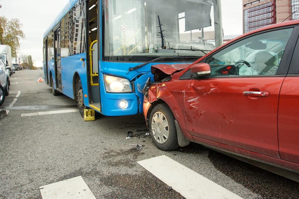 Tragic head-on collision between a car and a bus at a pedestrian crossing, underscoring the severity of traffic accidents.