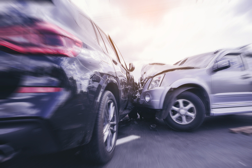 Dramatic collision between two cars, depicting the moment of impact with blurred motion on a cloudy day.