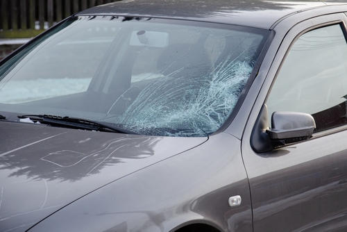 A close-up of a car with a shattered windshield, showing damage after an accident.