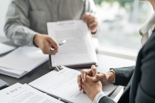 Two people sitting at a table during a formal consultation with a lawyer, reviewing legal documents.