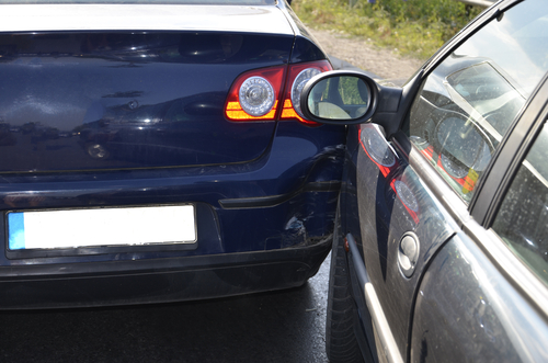 Close-up of a blue car with a sideswipe damage on its side after colliding with another vehicle.