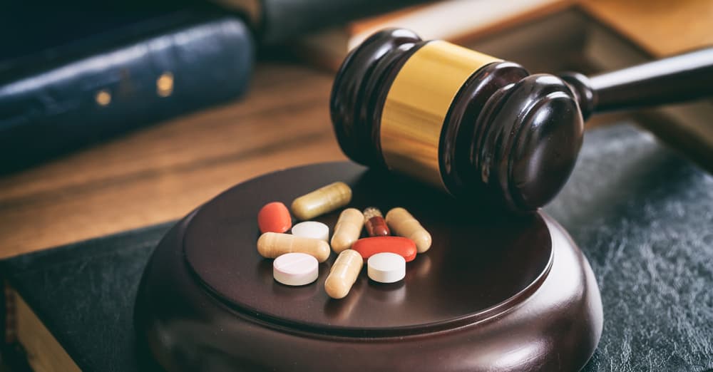 A judge's gavel resting beside various pills, symbolizing legal issues related to drug use.