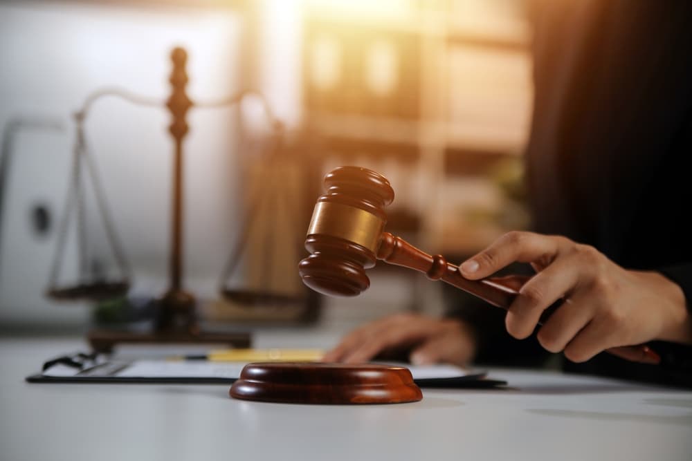 A judge holding a gavel in a courtroom setting, with legal scales in the background.